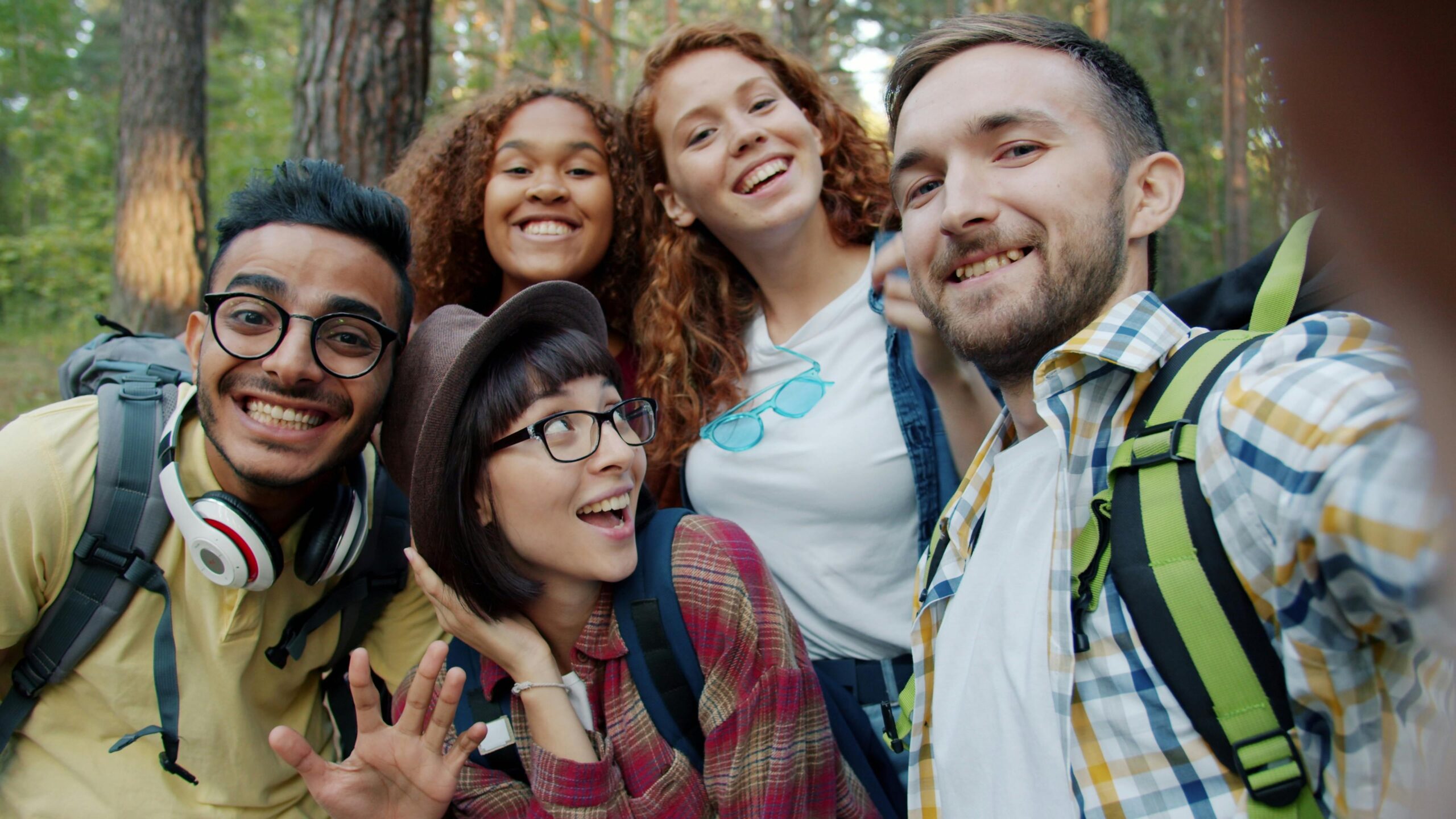 A group of diverse friends enjoying a fun selfie in a scenic forest together.